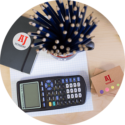 AJ Tutoring provides math tutoring supplies including a calculator, notebook adorned with the AJ Tutoring logo, and a mug filled with pencils, all placed on a piece of graph paper.